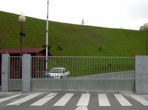 Un coche blanco está aparcado delante de una valla.