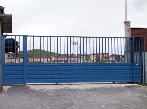 Una puerta corrediza azul está abierta a un estacionamiento.
