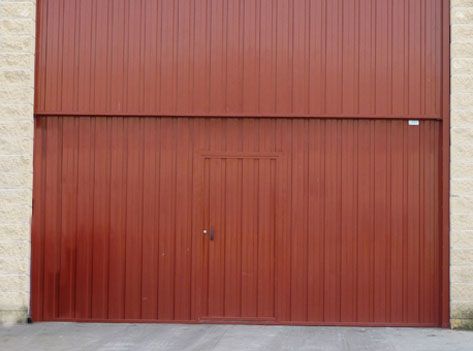 Una gran puerta de garaje roja se encuentra frente a un edificio de ladrillos.