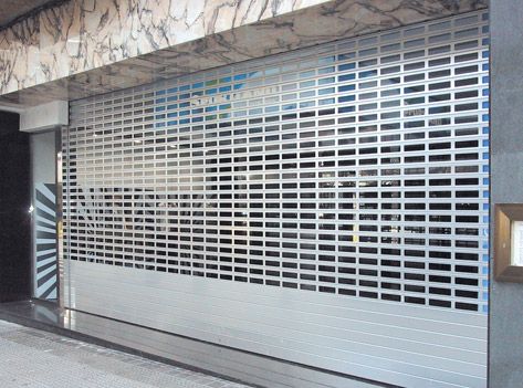Un escaparate con una persiana metálica encima.
