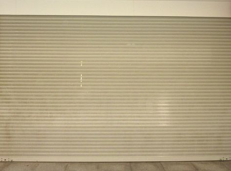 Una puerta enrollable blanca está cerrada en una habitación vacía.