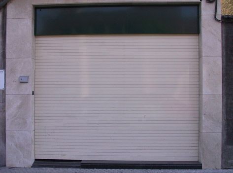 Una puerta de garaje blanca con una parte superior verde está cerrada.