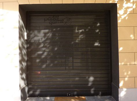 Una puerta de garaje negra está colocada al costado de un edificio.