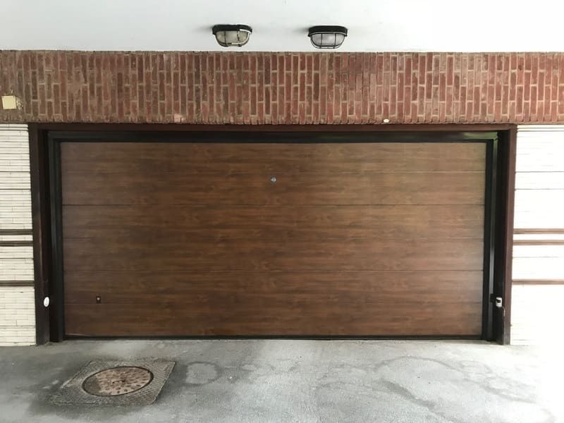 Una puerta de garaje de madera con una pared de ladrillos detrás.