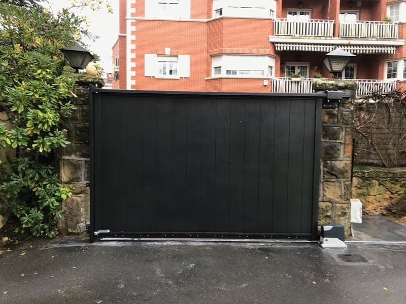 Una puerta negra está abierta frente a un edificio de ladrillos.