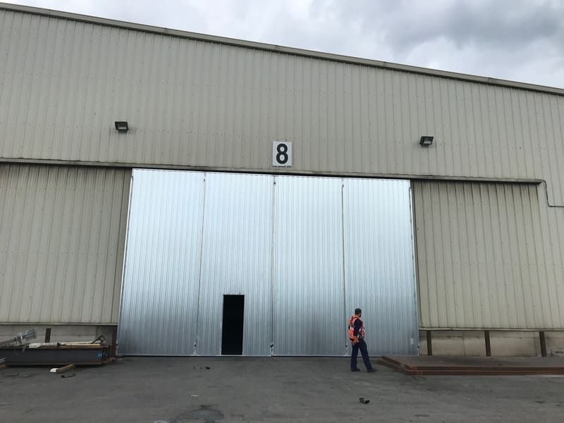 Un hombre está parado frente a una gran puerta de almacén con el número 8 en ella.