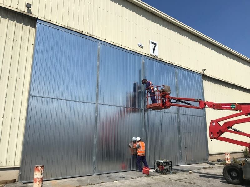Un grupo de hombres está trabajando en una gran puerta de metal.