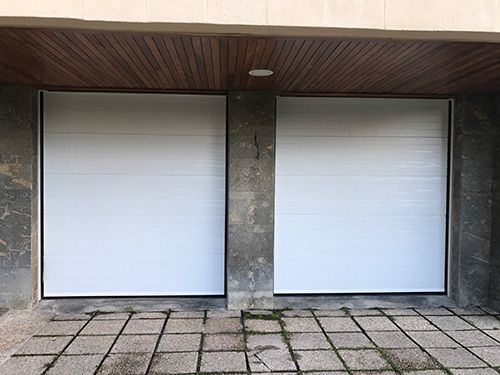 Un par de puertas de garaje blancas se encuentran frente a un edificio.