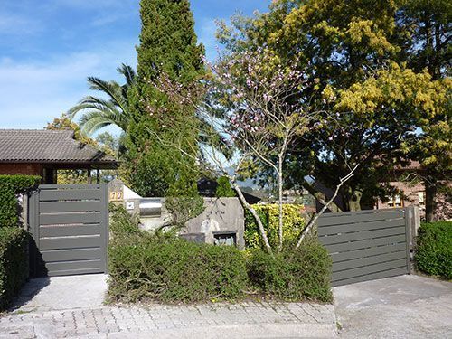 Una casa con una valla y árboles delante de ella.