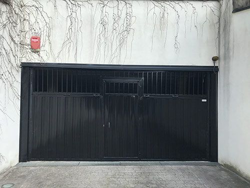 Una puerta de garaje negra está abierta en un estacionamiento.