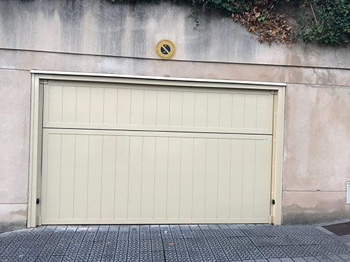 Una puerta de garaje blanca con un cartel de no estacionar en el costado.