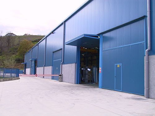 Un gran edificio azul con una barrera roja delante.