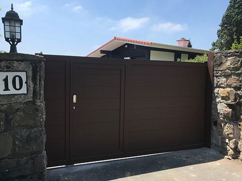 Una puerta marrón con el número 10 está frente a una casa.