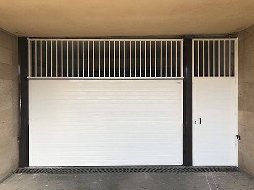 Una puerta de garaje blanca con una barandilla negra y una puerta.