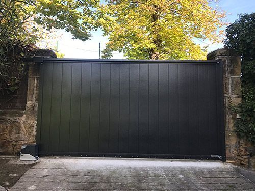 Una puerta corrediza negra se encuentra frente a una pared de piedra.