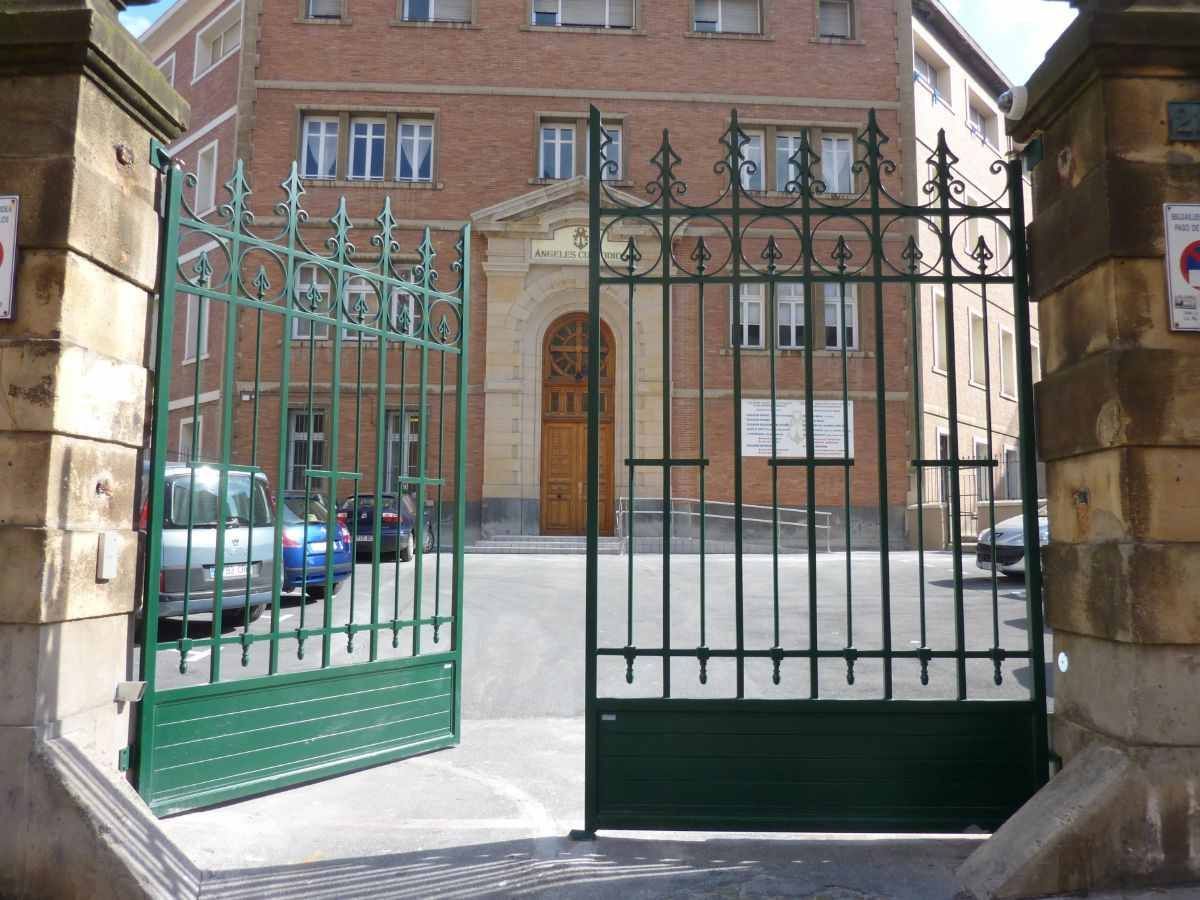 Una puerta verde está abierta frente a un edificio de ladrillo.