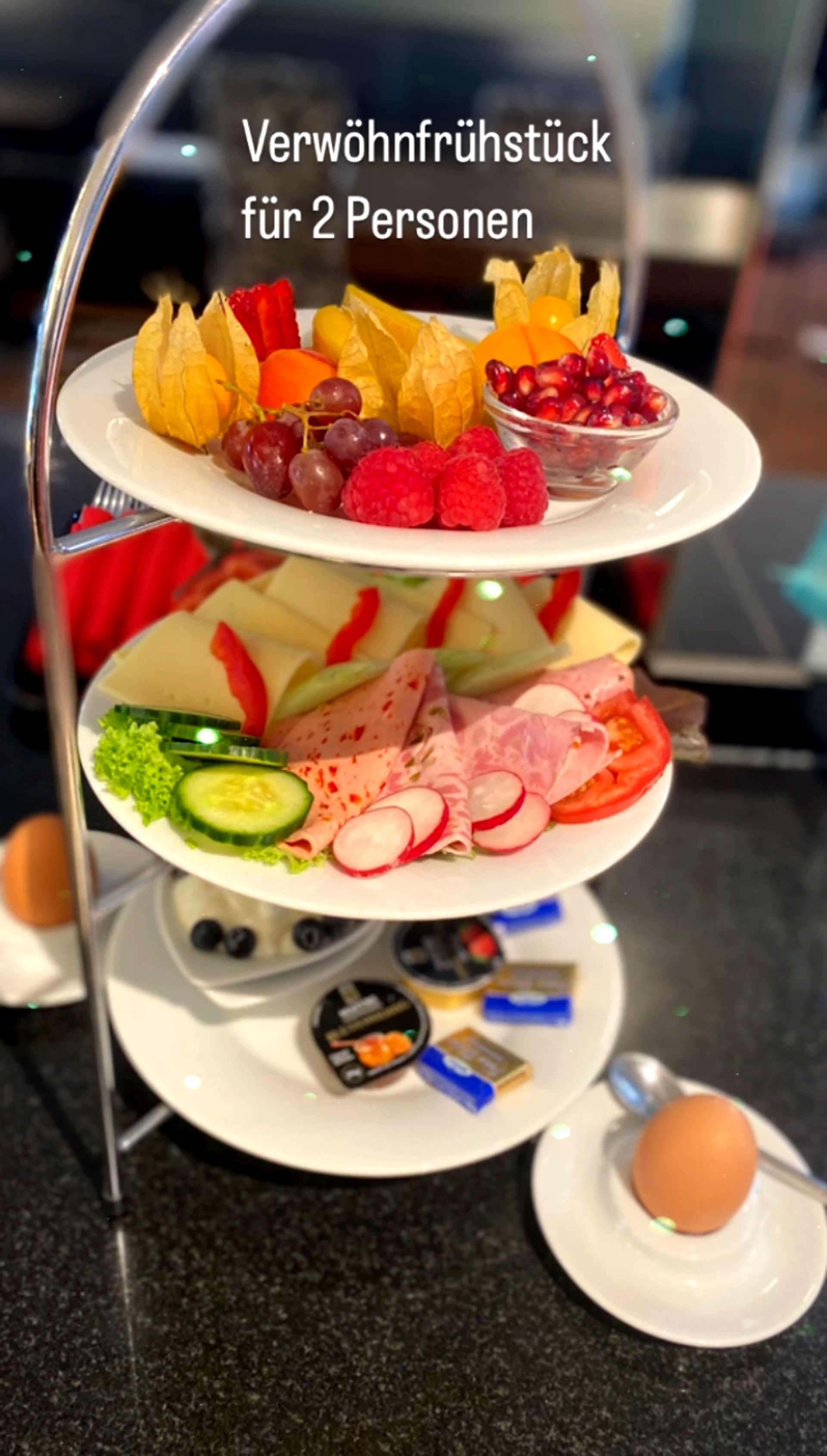 Etagere mit dem Verwöhnfrühstück für 2 Personen bestehend aus Obst, Wurst, Käse, Marmelade sowie je einem gekochten Ei