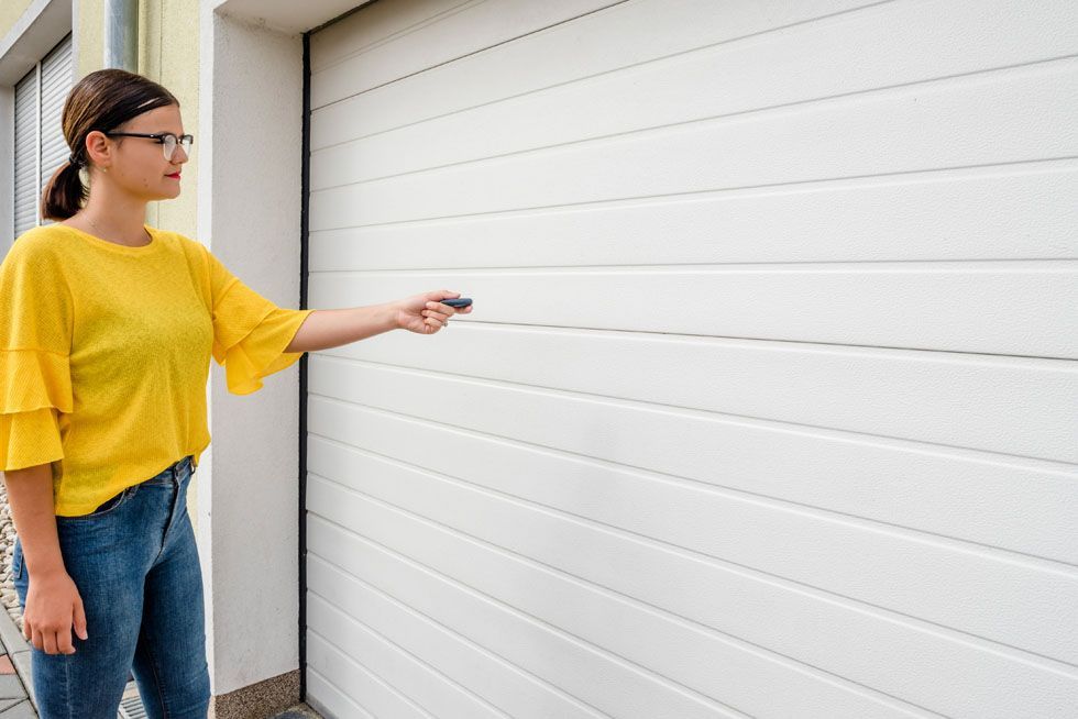 femme ouvrant une porte de garage automatique avec une télé commande