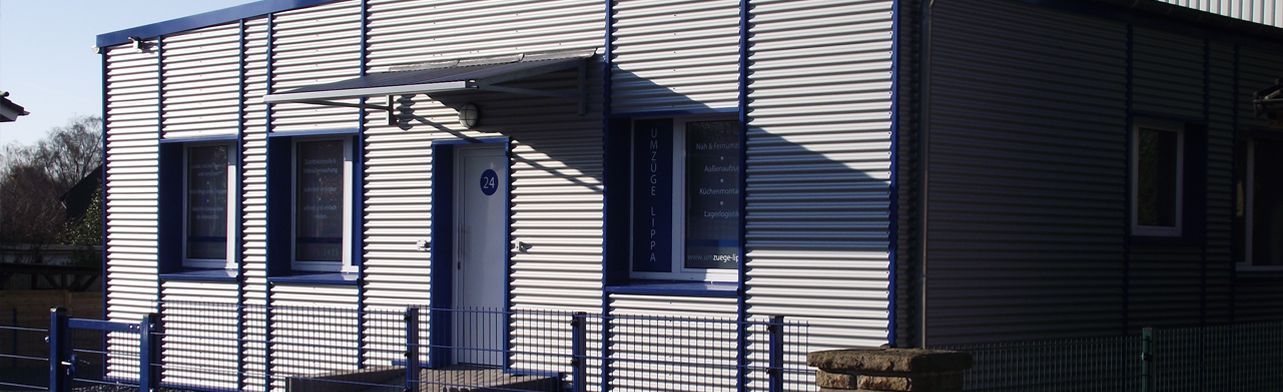 Ein weißes Haus mit einem blauen Zaun davor.