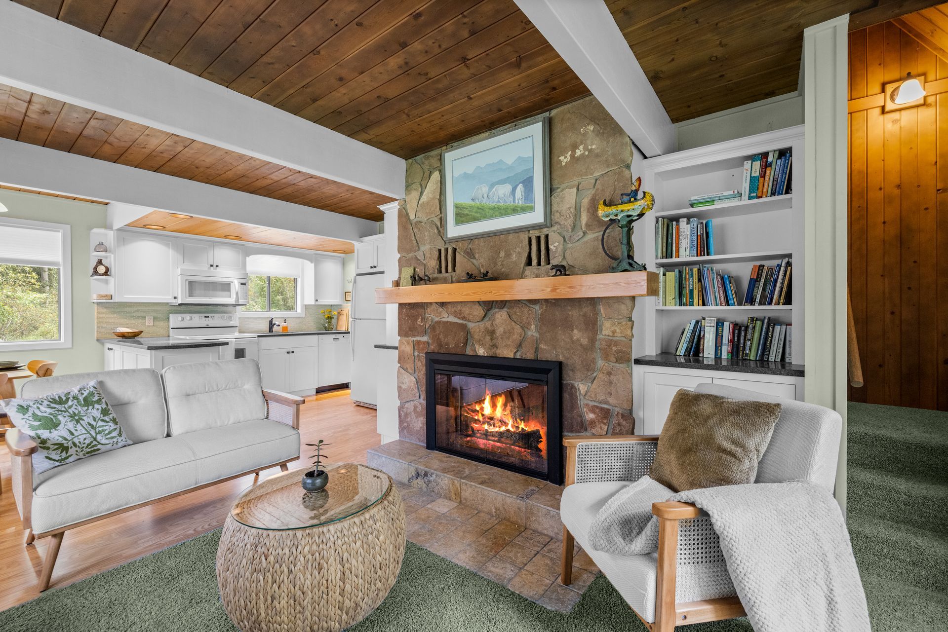 Open-concept living room and kitchen featuring yellow couches, a wooden coffee table, and a kitchen island with bar stools.