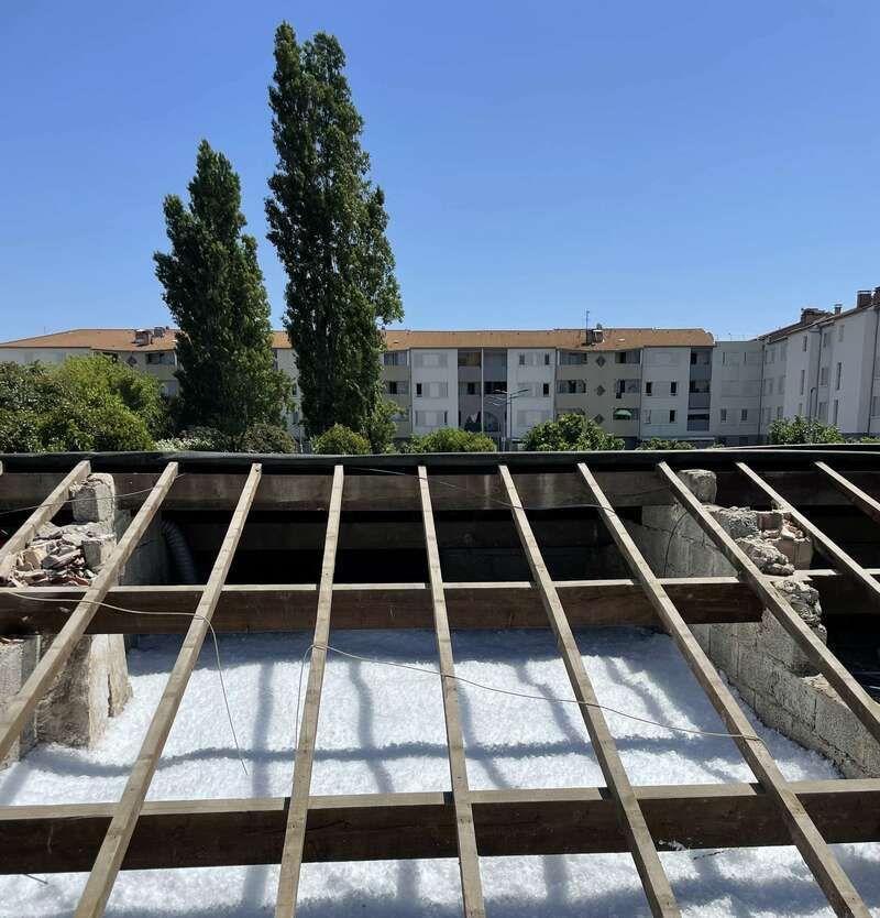 Un toit avec beaucoup de poutres en bois et un bâtiment en arrière-plan