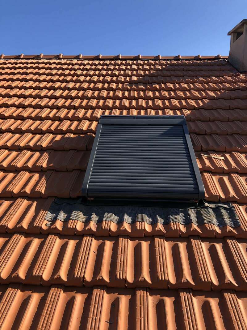 Un toit avec une fenêtre dessus et un ciel bleu en arrière-plan