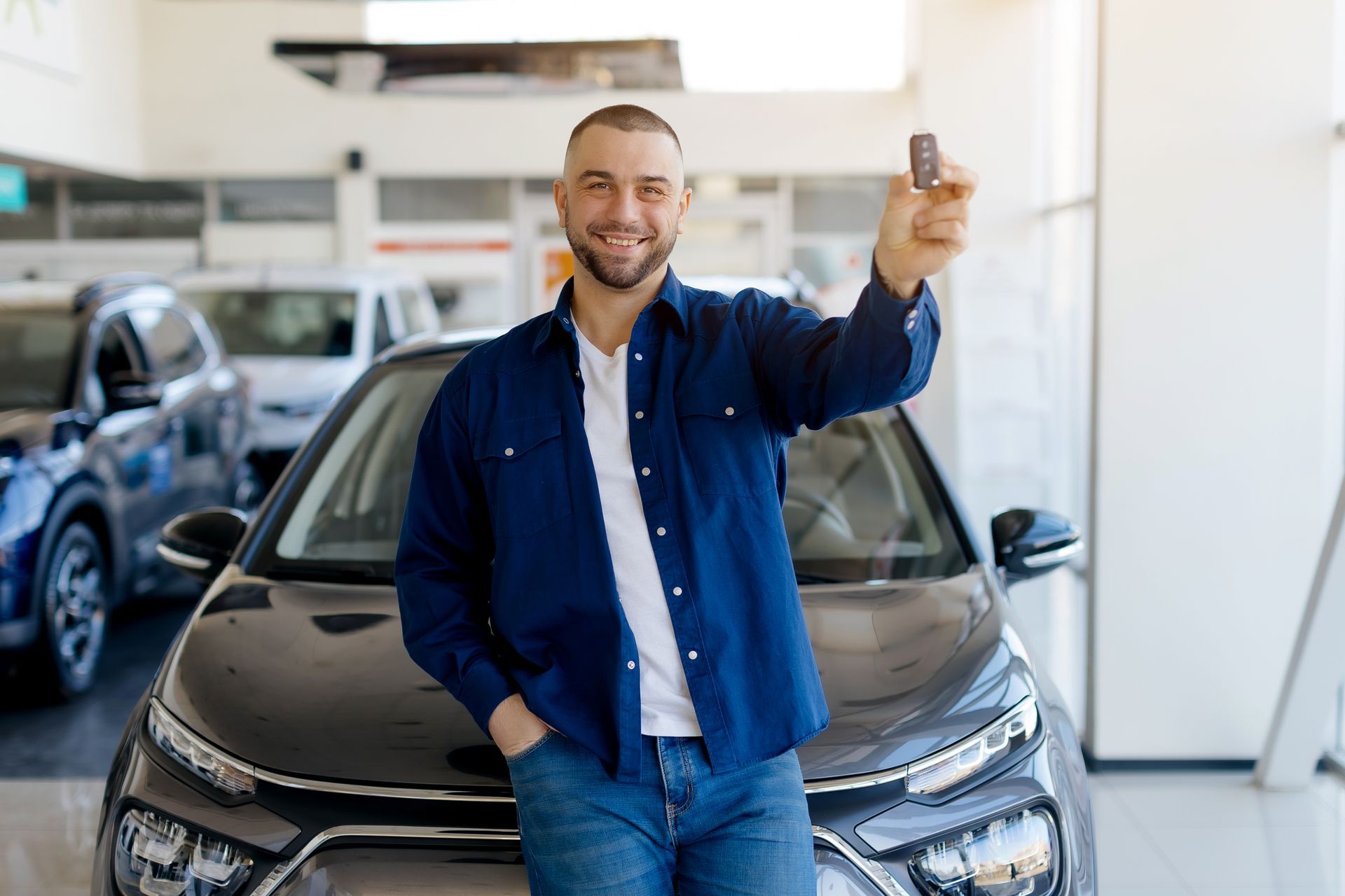 Homme adossé au capot d'une voiture avec la clé dans la main