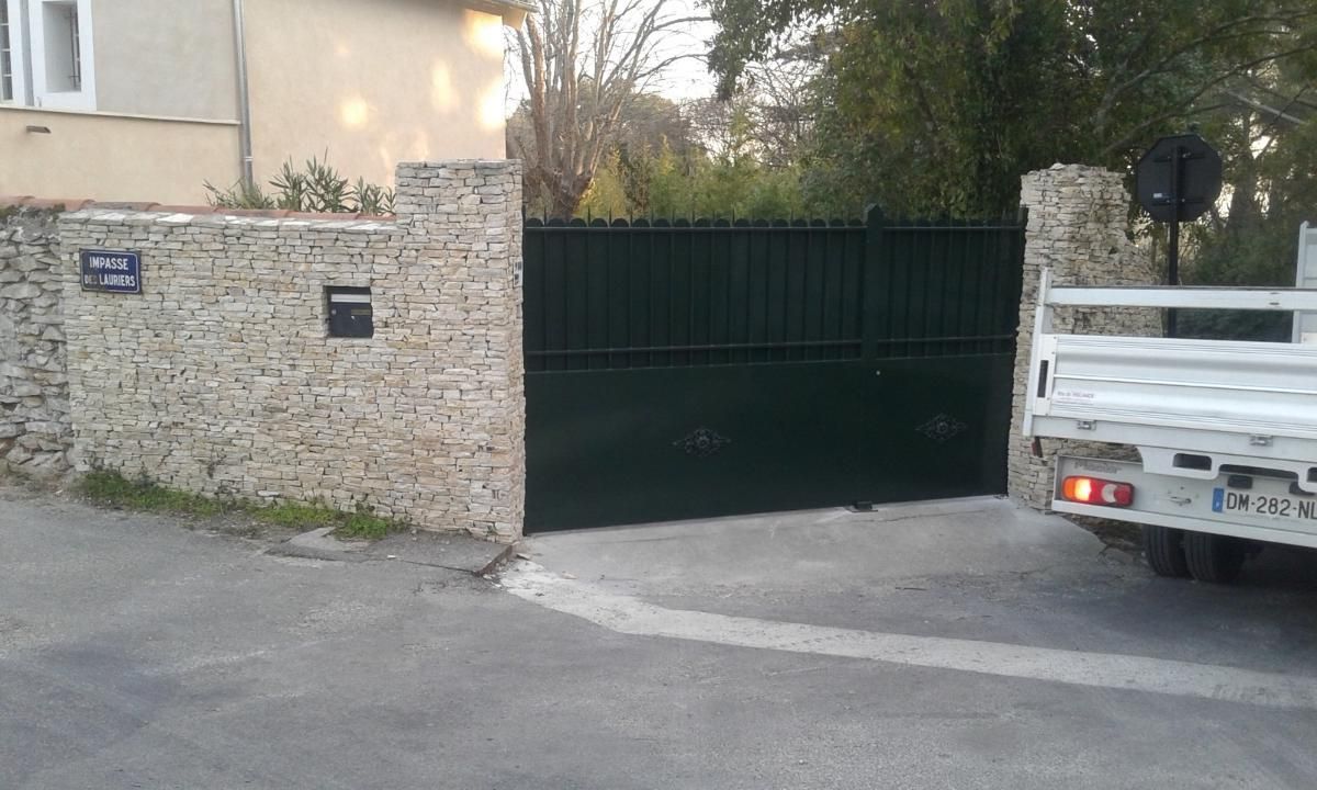 Portail en métal noir avec muret en pierre