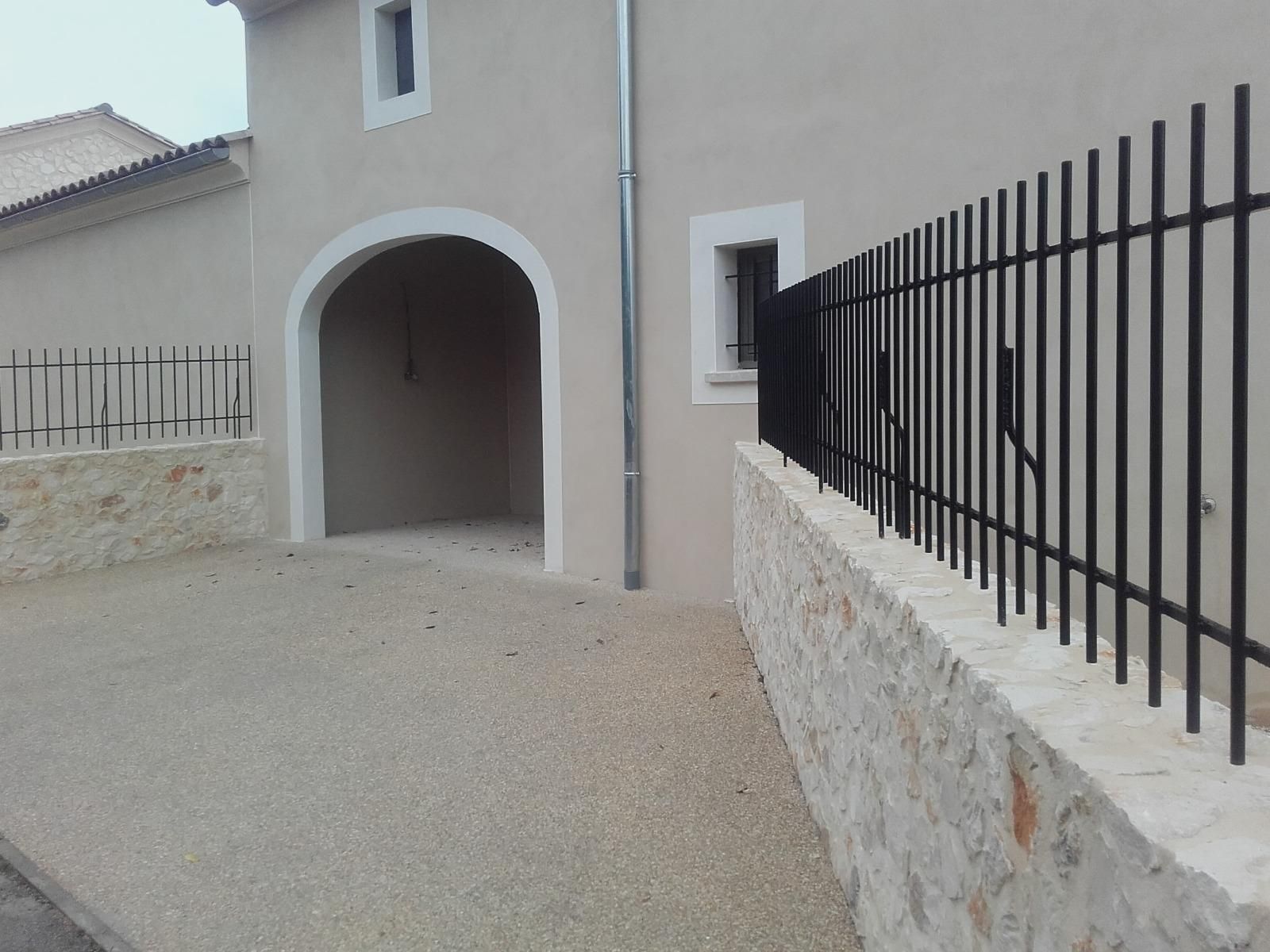 Clôture métallique sur un muret en pierre