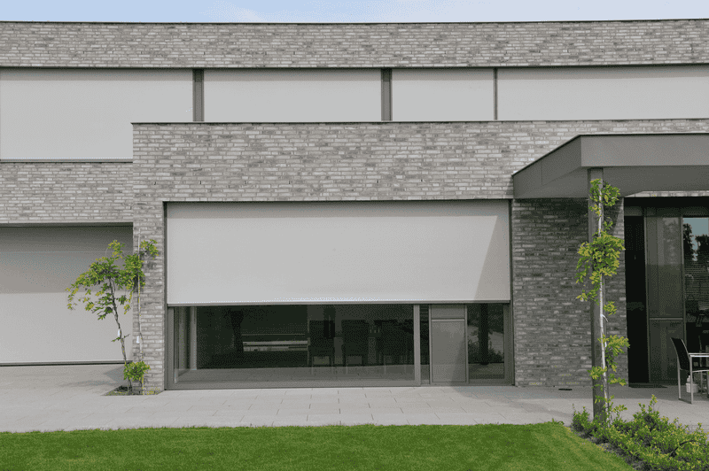 Edificio moderno de ladrillo gris con cortinas exteriores retráctiles.