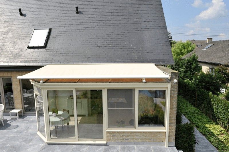 Ampliación de terraza acristalada con techo y molduras de color beige y ventanas de vidrio