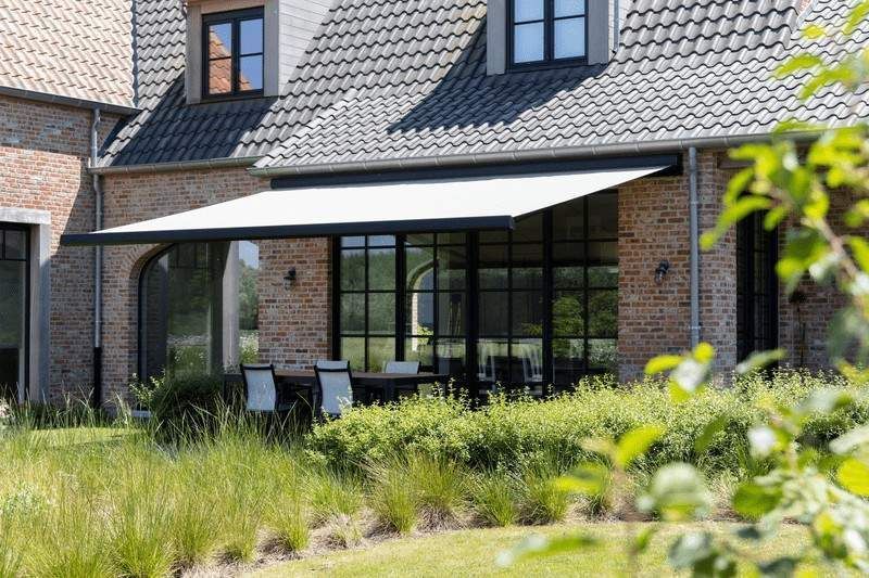 Un toldo blanco se extiende desde un edificio de ladrillo con ventanas con marco negro