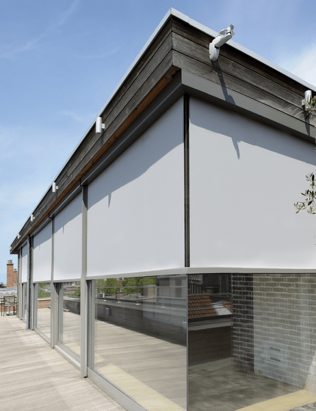 Persianas enrollables grises para exterior sobre las ventanas de vidrio del edificio, día soleado.