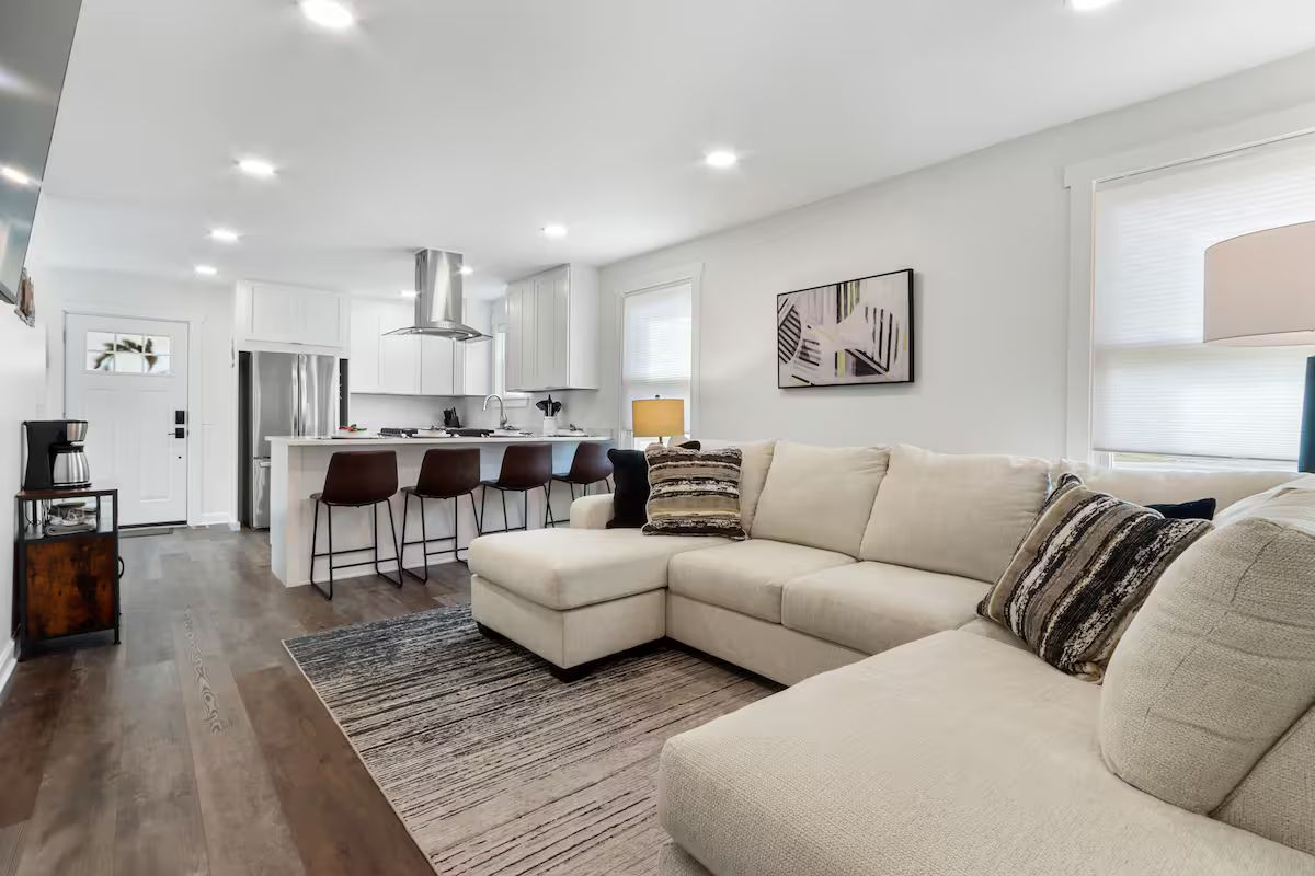 A living room with a large sectional couch and a kitchen in the background.