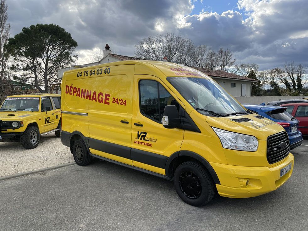 Fourgonnette de service jaune avec l'inscription Dépannage 24.24 sur le côté, garée à l'extérieur.