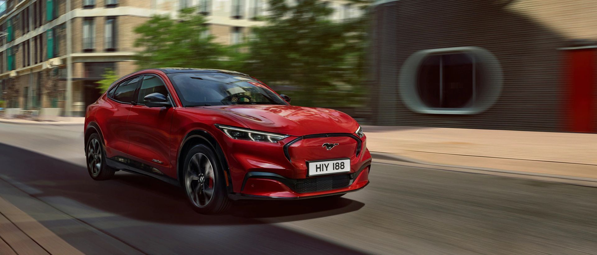 Une Ford Mustang Mach-E rouge dans une rue de la ville.