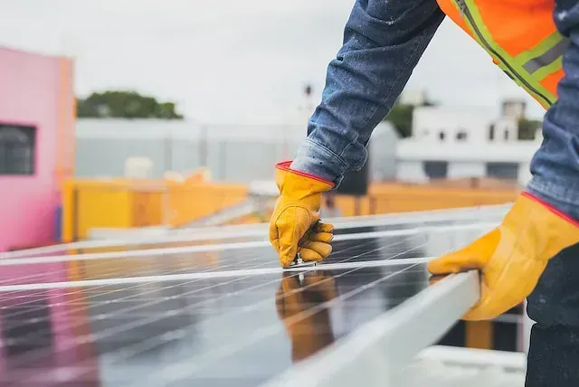 Un hombre está instalando paneles solares en un tejado.