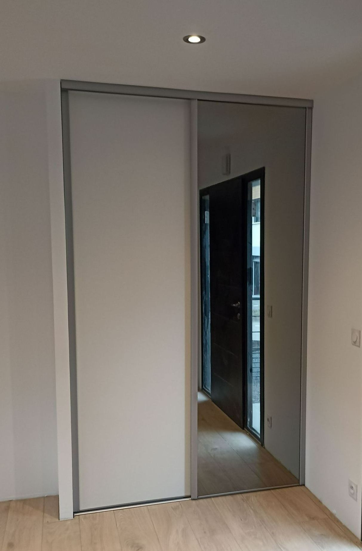 Un placard d'entrée avec un miroir sur les portes coulissantes