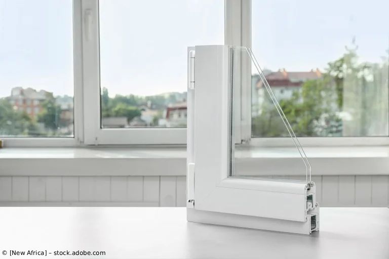 Weißer Faltfensterbegrenzer auf einer Fensterbank neben einem offenen Fenster mit Stadtblick