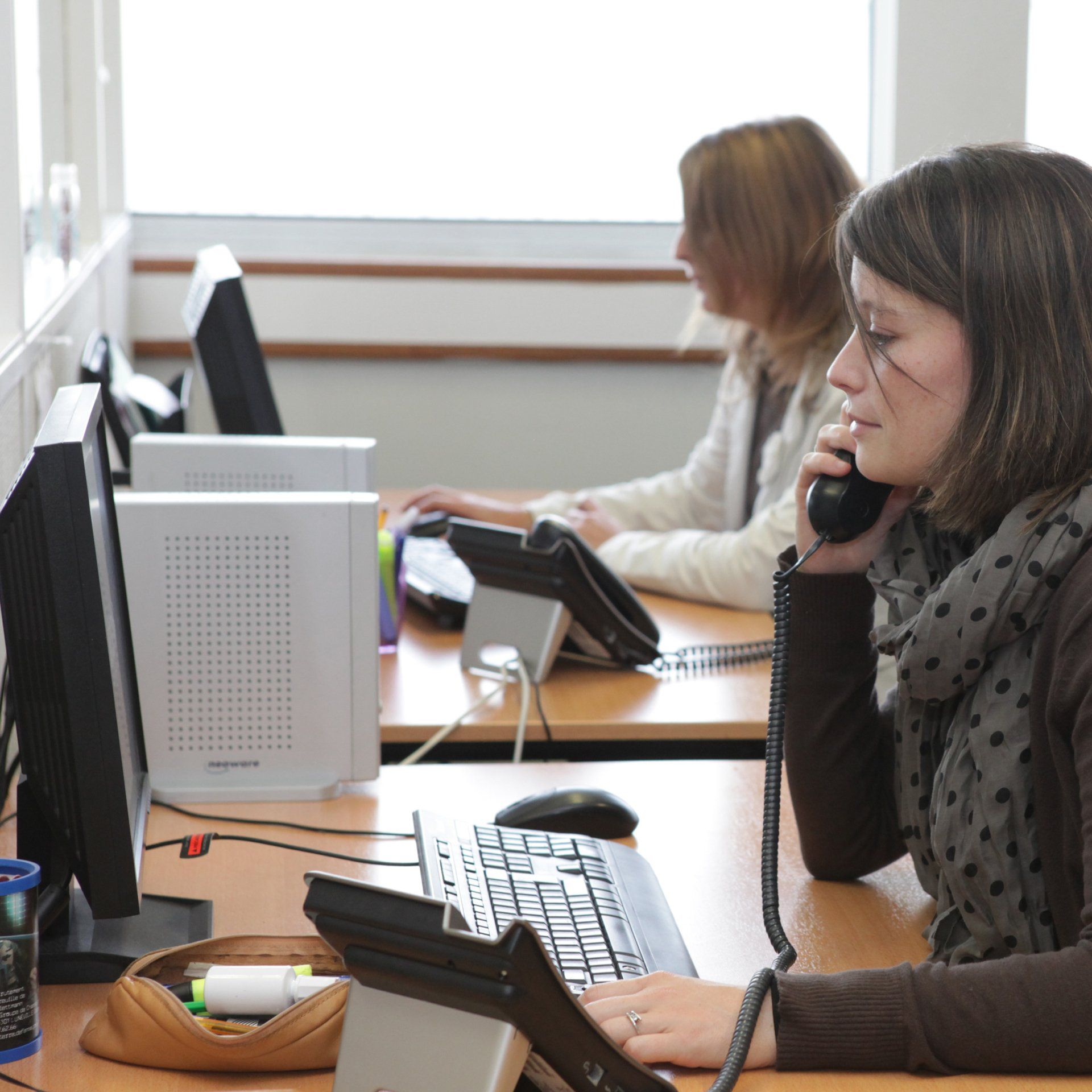 Femme au foulard au téléphone avec une autre femme en arrière-plan