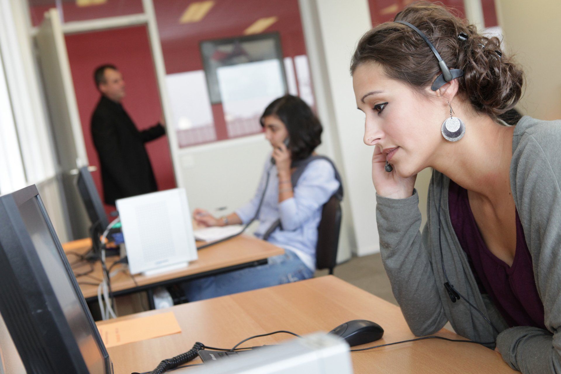 Deux jeunes femmes au téléphone avec un homme en arrière-plan