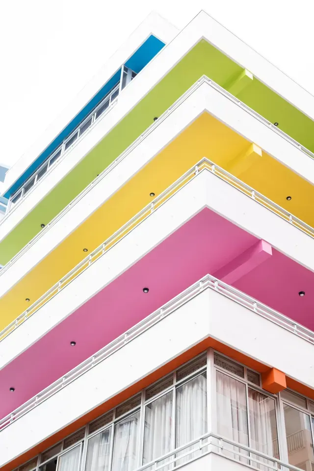 Edificio colorido con balcones en capas de azul, verde, amarillo y rosa.
