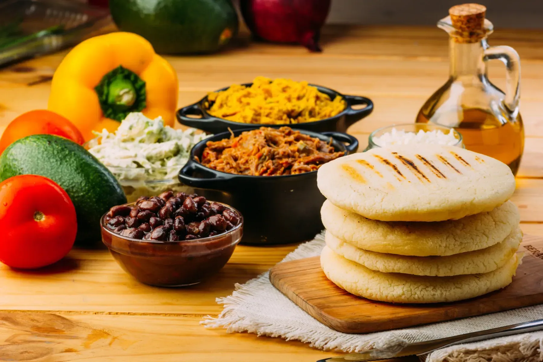 Arepas con diversos rellenos como frijoles, carne y queso, acompañados de verduras frescas.