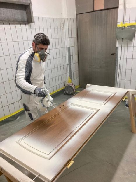 Malermeister Heinrich Olfert Maler sprüht weiße Farbe auf eine Holztür