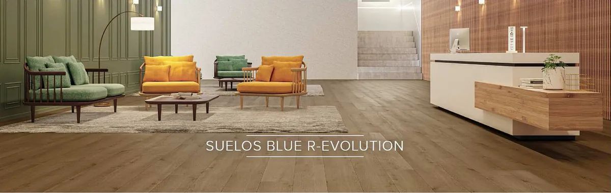 Una moderna sala de espera de oficina con sillas verdes y naranjas, pisos de madera y un mostrador de recepción blanco.
