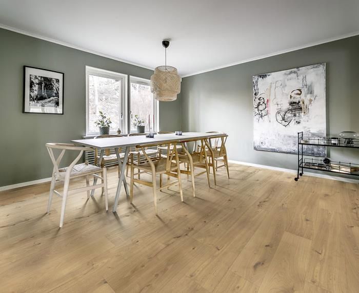 Suelo de madera de color marrón claro con tablones verticales que presentan patrones de nudos y vetas.