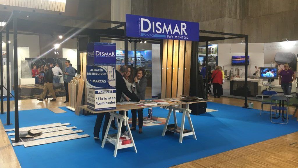 Un grupo de personas están de pie alrededor de una mesa en un stand de Dismar.