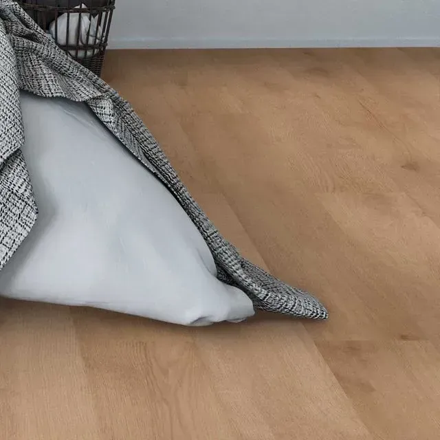 Una cama con una manta y una almohada sobre un suelo de madera.