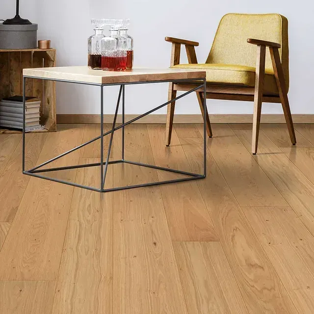 Una sala de estar con pisos de madera y una mesa de café y una silla.