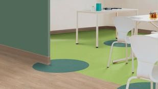 Un comedor con mesa y sillas y suelo verde.